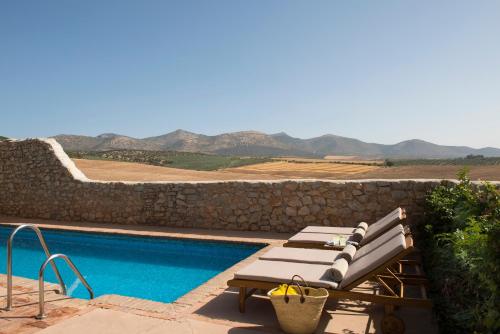 a pool with a bench next to a stone wall at Hotel Cortijo del Marqués in Albolote