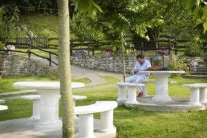 a man sitting on a bench in a park at Hotel & Spa Villa de Mestas in Cangas de Onís