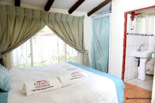 um quarto com uma cama com um lavatório e uma janela em Harmony Guest House em Joanesburgo