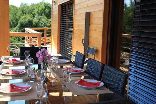 - une table avec des serviettes rouges et des verres à vin sur la terrasse dans l'établissement Au Chant du Riou, à Saint-Michel-de-Chaillol