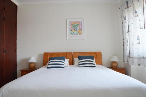 a bedroom with a white bed with blue and white pillows at Baleal Tower Bay Apartment in Ferrel