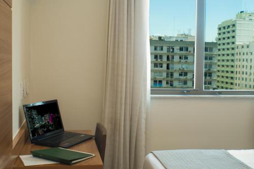 a laptop computer sitting on top of a desk in front of a window at Américas Granada Hotel in Rio de Janeiro