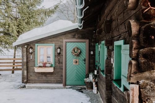 a wooden house with a green door and snow on it at Knusperhauschen Sonnegg in Flachau