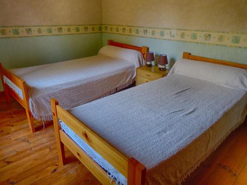 two beds in a small room with wooden floors at Gîte "L'Orée du Bois" in Beaune-sur-Arzon