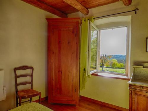 1 dormitorio con ventana, armario de madera y silla en Gîte "L'Orée du Bois", en Beaune-sur-Arzon