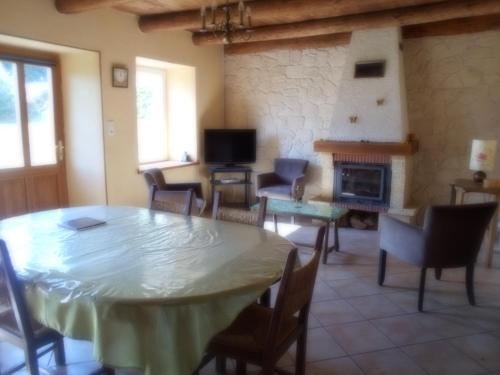 een woonkamer met een tafel en een open haard bij Gîte "L'Orée du Bois" in Beaune-sur-Arzon