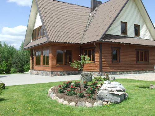a log cabin with a flower bed in front of a house at Country Houses Vidų Sodyba in Utena