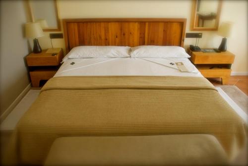 a large bed in a bedroom with two night stands at Hotel Cigarral el Bosque in Toledo