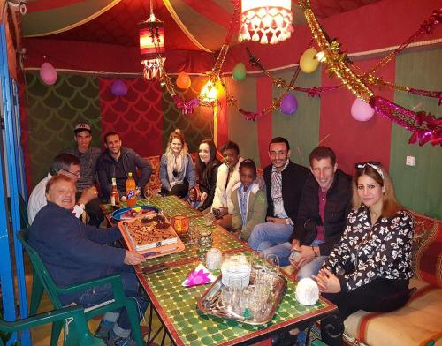 a group of people sitting around a table with a cake at Maison d'hôtes Cité Portugaise in El Jadida