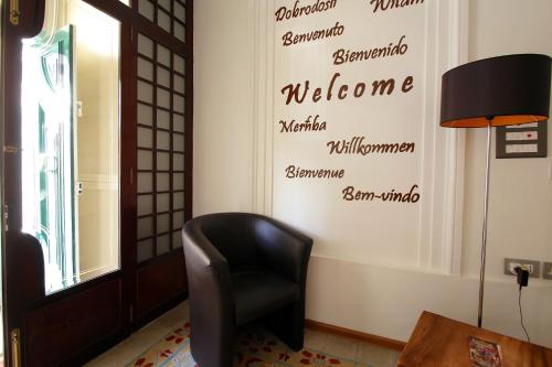 a black chair in a room with a welcome wall at Corner Hostel in Sliema