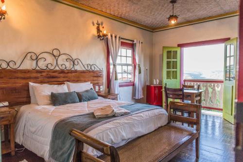 a bedroom with a large bed and a table and chairs at Pousada Vila Mineira in Lavras Novas