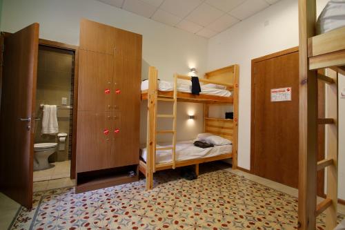 a bedroom with bunk beds and a bathroom with a toilet at Corner Hostel in Sliema