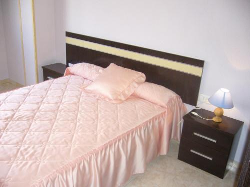 1 dormitorio con 1 cama y mesita de noche con lámpara en Piso en calle Campo, en Tomelloso