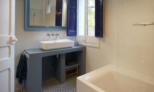 ein Badezimmer mit einem Waschbecken, einem Spiegel und einer Badewanne in der Unterkunft Can Calixto in Aiguafreda