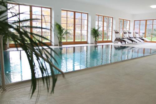 uma grande piscina interior com cadeiras e janelas em Hotel Hochsteg Gütl | Traunsee Salzkammergut em Ebensee