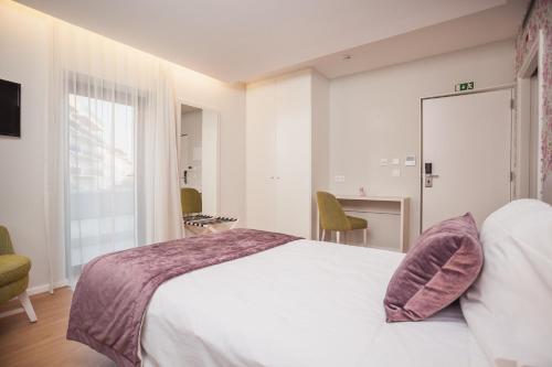 a bedroom with a large white bed and a desk at Essence Inn Marianos Hotel in Fátima