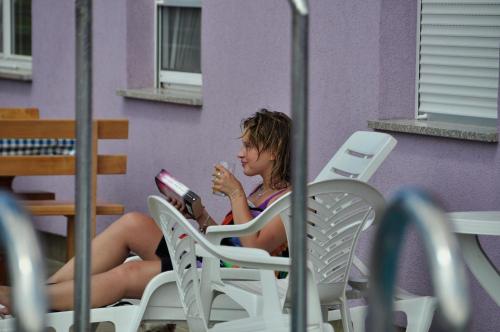 a woman sitting in a chair reading a book at Vila in Lavanda in Fažana