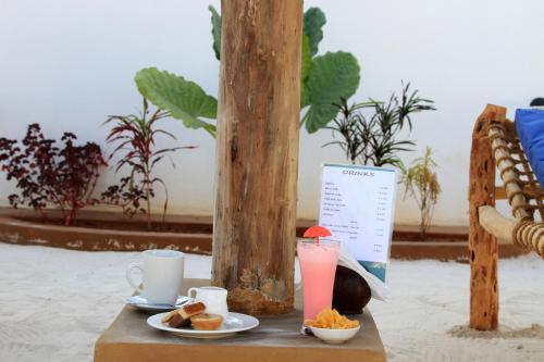 a table with a plate of food and a drink at Kiganja in Matemwe