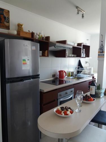 una cocina con nevera y una bandeja de fruta en una mesa. en Apartamento Peñuelas, en Coquimbo