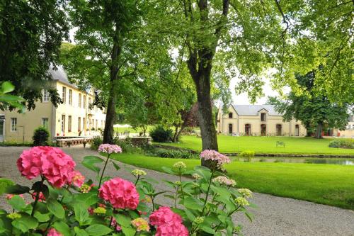 a garden with pink flowers in front of a house at Château de Bellefontaine - Teritoria in Bayeux