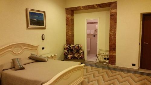 a bedroom with a bed and a chair and a mirror at Hotel Croce Di Malta in Rome