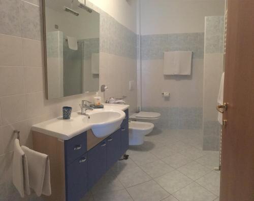 bagno con lavandino, servizi igienici e specchio di Mary Apartments a Brenzone sul Garda