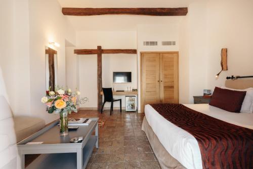 a hotel room with a bed and a table with a vase of flowers at Les Bergeries De Palombaggia in Porto-Vecchio