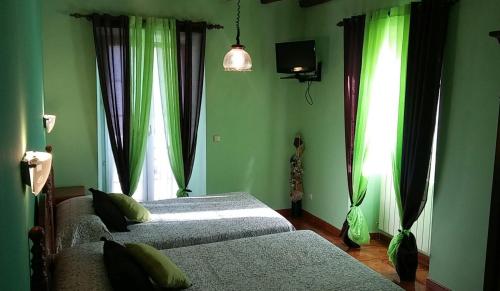 two beds in a bedroom with green walls and windows at Hostal Ekaitza in Lesaka
