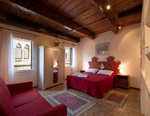 een slaapkamer met een rood bed en een bank bij Casa San Severo in Venetië