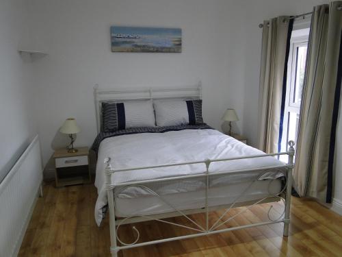 a bedroom with a white bed and a window at Tri Ard House Derry City Centre town house in Derry Londonderry