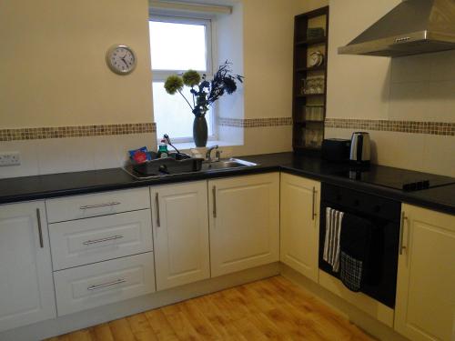 eine Küche mit weißen Schränken, einem Waschbecken und einem Fenster in der Unterkunft Tri ard house Derry city centre STILL OPEN in Derry Londonderry