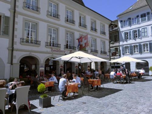 a group of people sitting at tables in front of a building at Hostellerie du XVI Siècle in Nyon