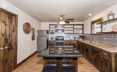 a kitchen with wooden cabinets and a ceiling fan at Vineyard Trail Cottages- Adults Only in Fredericksburg