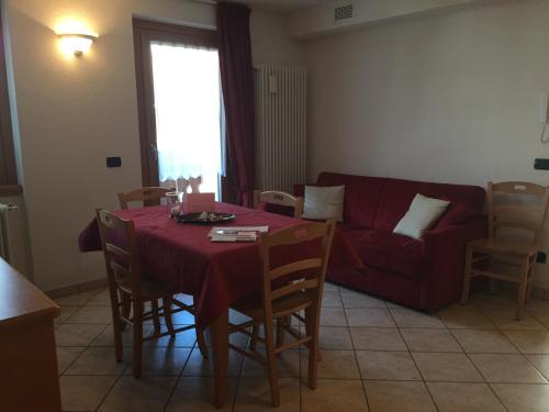 a living room with a table and a red couch at Chalet Del Bosco in Valdisotto