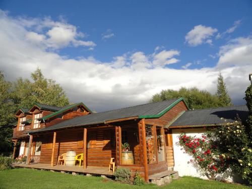 uma cabana de madeira com um alpendre e cadeiras num quintal em Las Vertientes Lodge em San Martín de los Andes