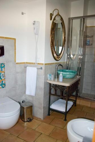 a bathroom with a sink and a toilet and a mirror at San Francesco Resort in Agropoli