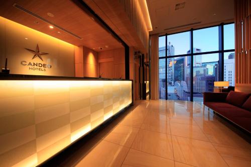 a lobby of a building with a sign on the wall at Candeo Hotels Tokyo Shimbashi in Tokyo