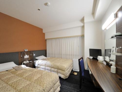 富山市にある富山マンテンホテルのベッド2台、薄型テレビが備わるホテルルームです。