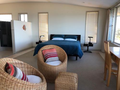 a bedroom with a bed and wicker chairs at OceanScape Luxury Beachfront Villas in Scotts Head