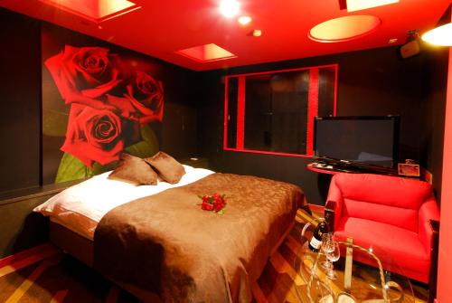 1 dormitorio con 1 cama y 1 silla roja en Hotel Joy (Love Hotel), en Onga
