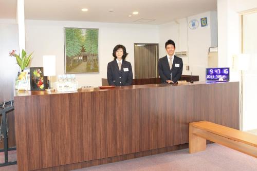 a couple of people standing at a reception desk at Hotel Innoshima in Onomichi