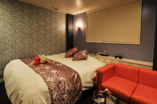 Habitación de hotel con cama y sofá rojo en Hotel Cube (Love Hotel), en Kitakyushu