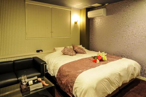 a hotel room with a bed with a chair and flowers on it at Hotel Cube (Love Hotel) in Kitakyushu