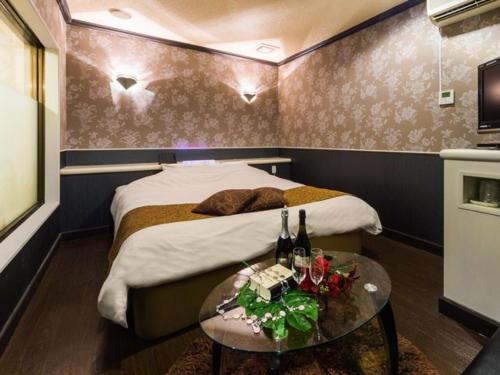 um quarto com uma cama e uma mesa com garrafas de vinho em Hotel TiAMO (Love Hotel) em Kitakyushu