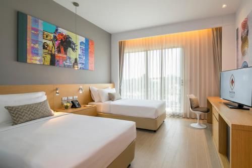 a hotel room with two beds and a television at Eastin Thana City Golf Resort Bangkok in Samutprakarn