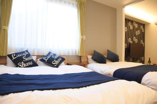 een hotelkamer met 2 bedden en een raam bij Ambiera Doza in Nagasaki