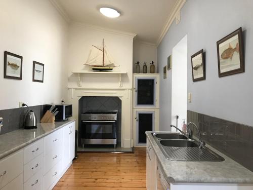 a kitchen with a sink and a fireplace at Armadale House - Kingscote in Kingscote