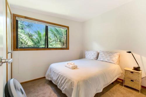 a bedroom with a white bed and a window at Karaka Sanctuary with Spa Pool by Waiheke Unlimited in Oneroa