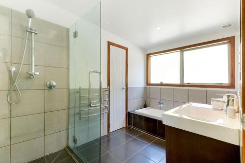 a bathroom with a shower and a sink and a tub at Karaka Sanctuary with Spa Pool by Waiheke Unlimited in Oneroa