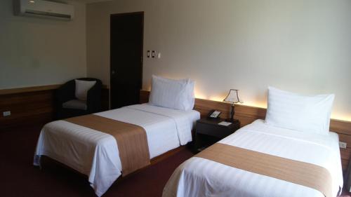 a hotel room with two beds and a chair at Grand Sierra Pines Baguio in Baguio